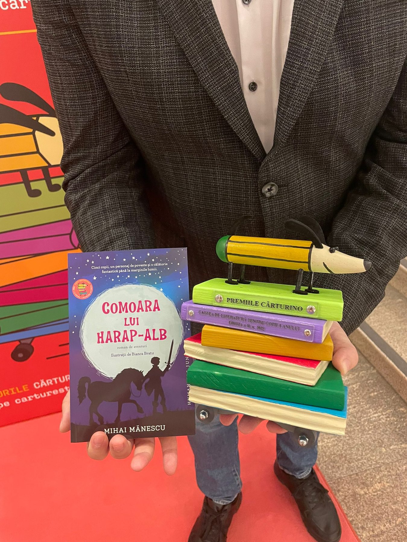 The novel held in hand next to the Cărturino Awards trophy.