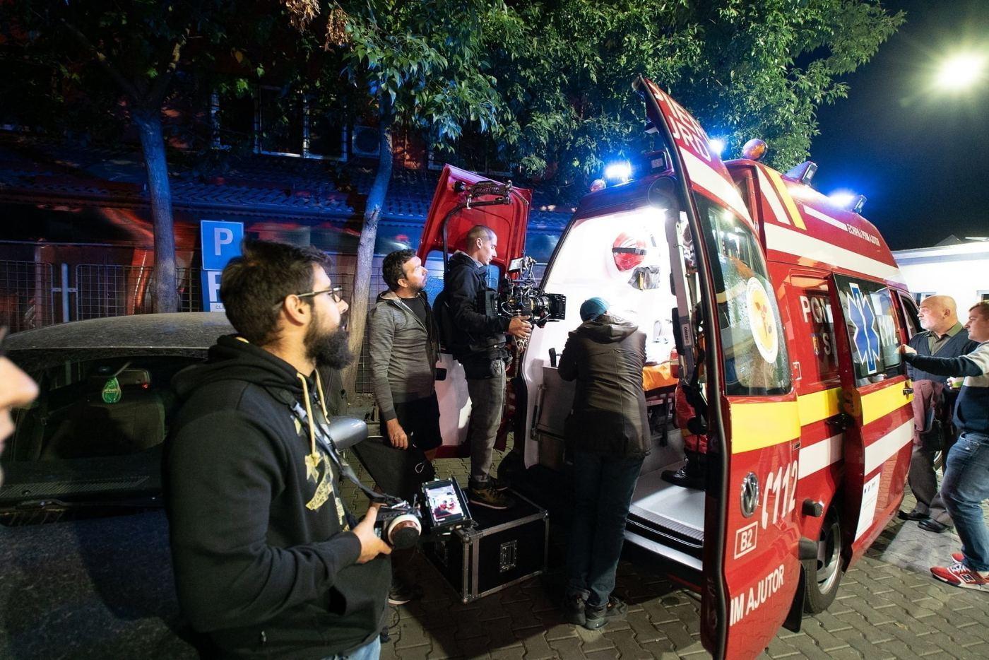 Echipa filmând noaptea lângă o ambulanță cu girofarurile aprinse