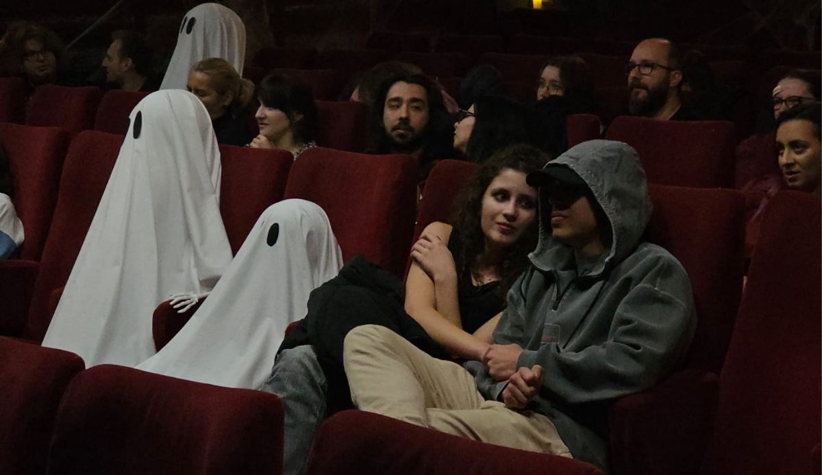 Spectatori și doi oameni costumați în fantome, în sala de cinema