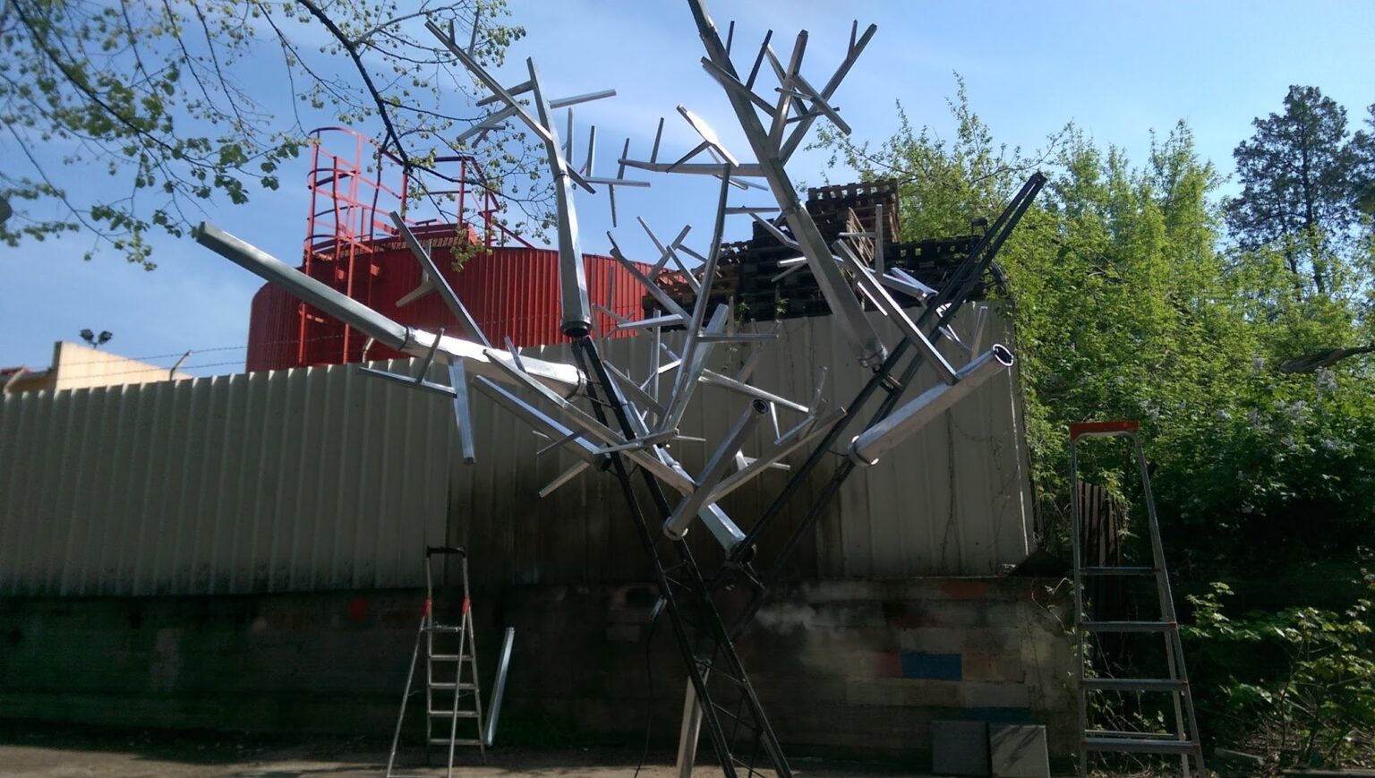 Structura copacului în timpul producției, cu ramuri metalice și echipamente de lucru.