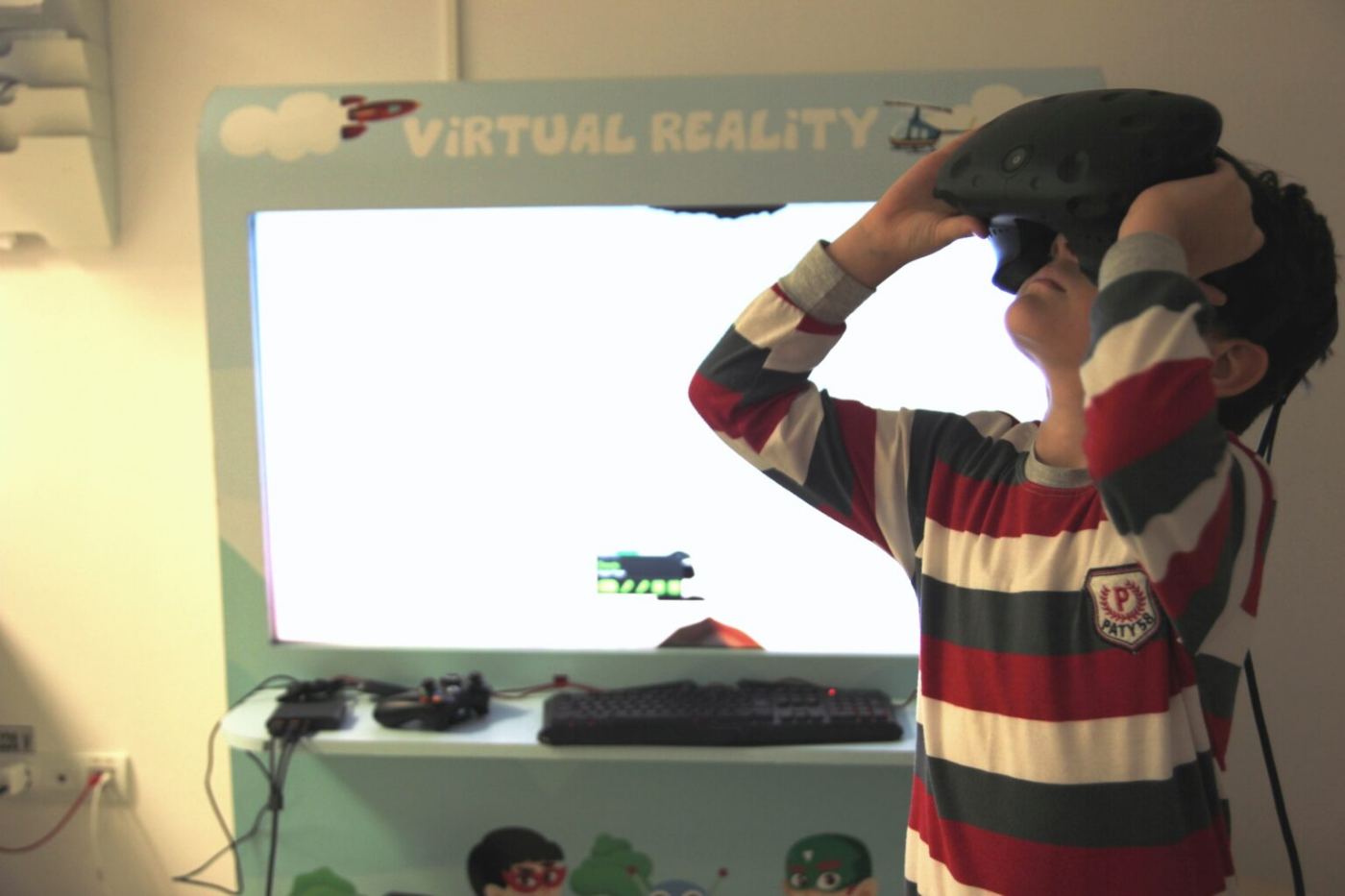 A child putting on the virtual reality headset, in front of the screen