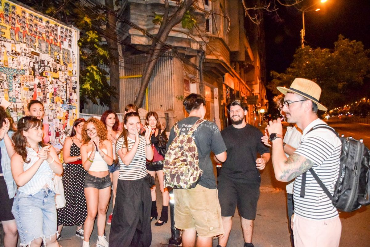 A group of volunteers gathered on the pavement, laughing, next to the poster board